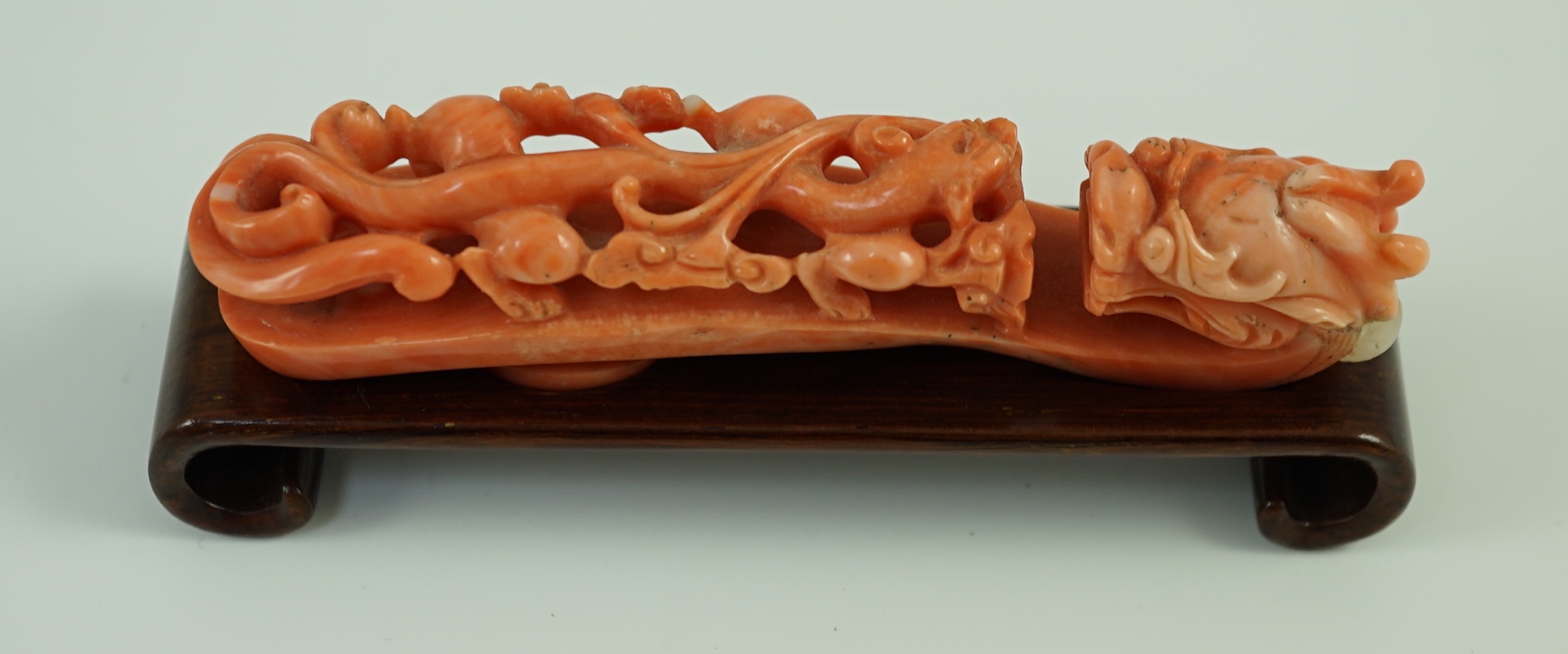 A rare Chinese coral 'dragon' belt hook 18th/19th century, 9.2 cm long, small loss to dragon horn, wood stand